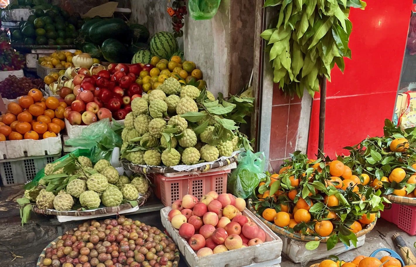 Market baskets full of fresh fruits, including clementines, apples, and guavas.