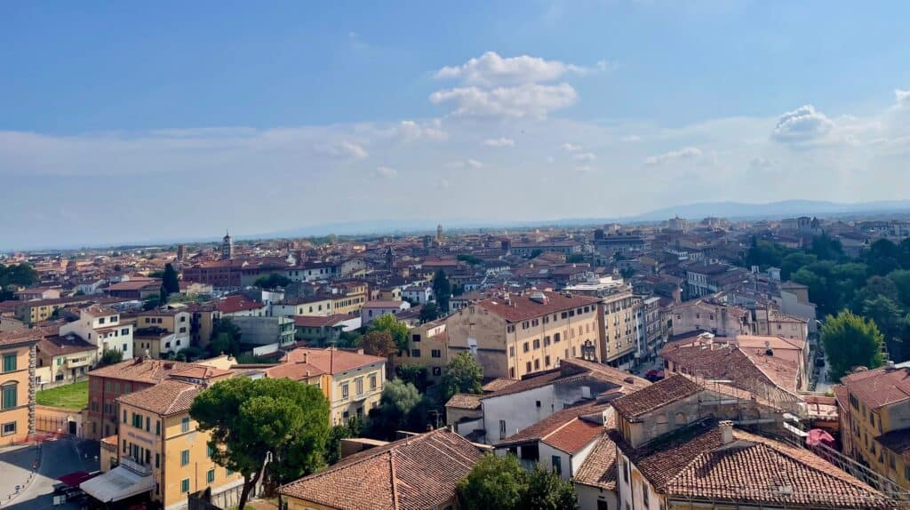 An aerial view of the red roofed buildings of Pisa from the top of the Leaning Tower of Pisa.