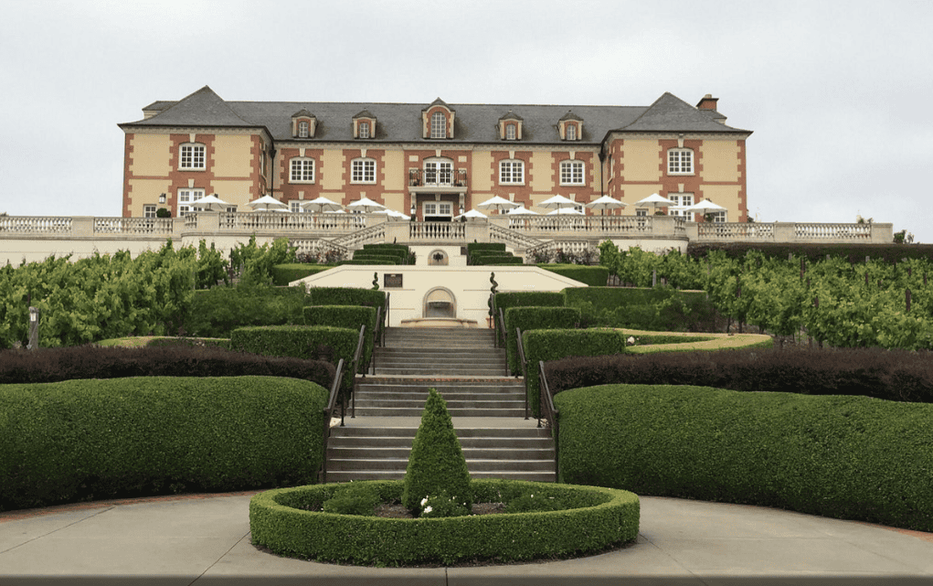 French Chateau looking building with trimmed hedges and grand stairs.