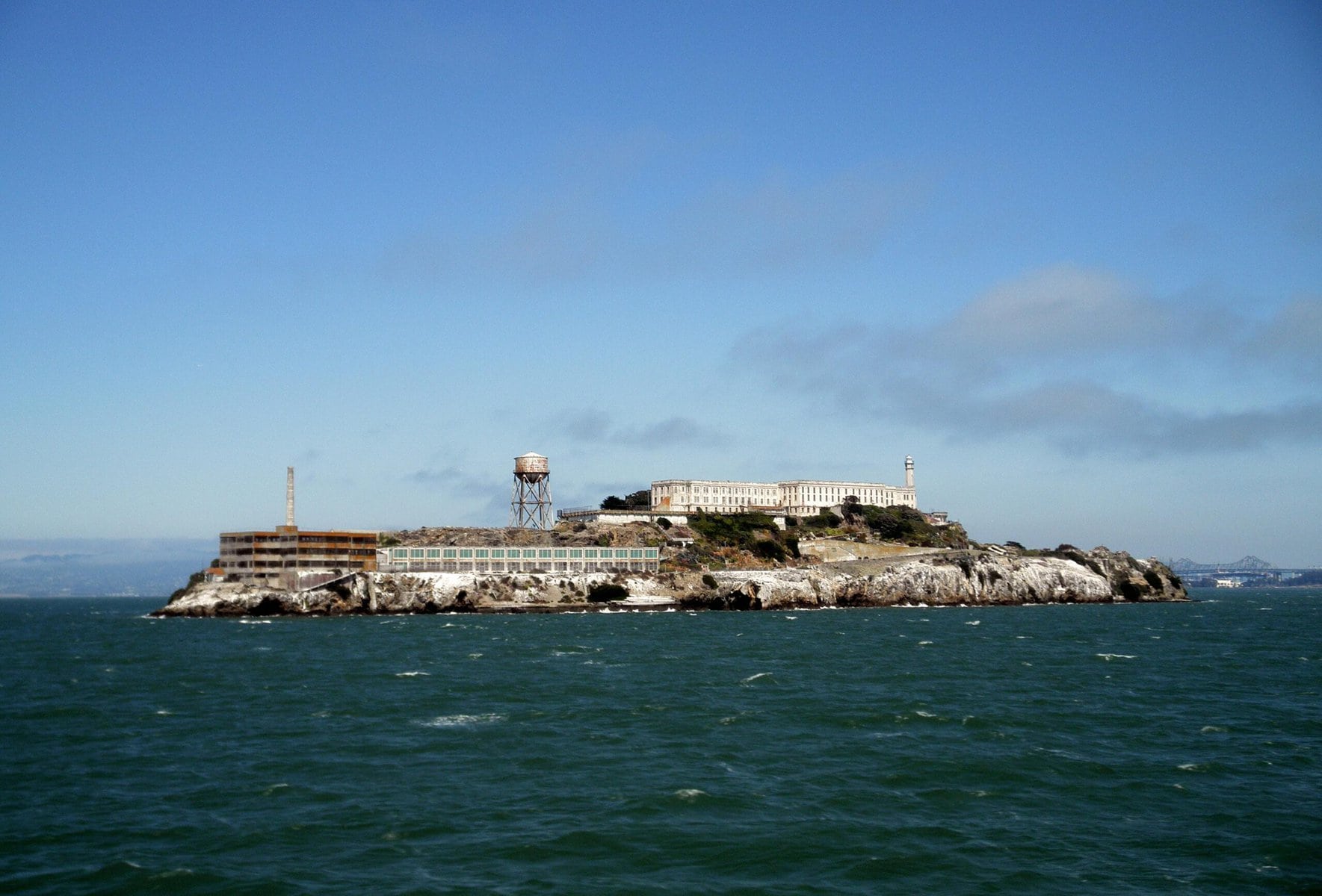 A view from the sea of Alcatraz island prison with with whitecaps in the water surrounding the island.